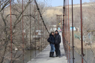 Genç çift ayakta kablolar, mutlu aile kavramı ile eski köprü
