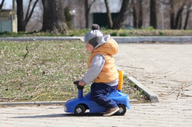 Şirin çocuk bahar parkta mavi çocuk araba sürme