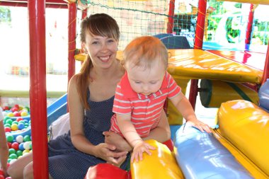 Genç Anne küçük bebek eğlence parkı ile mutlu bir aile gülümseyen