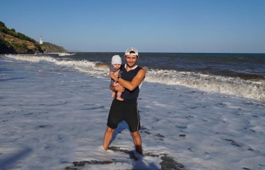 Sahilde sevimli bebek ile genç baba portresi