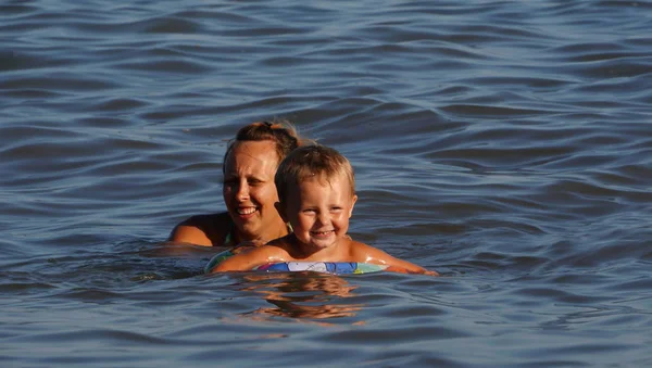 Matka i słońce pływackie w morzu. Letnie wakacje na plaży morskiej. — Zdjęcie stockowe