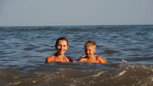 Anne ve güneş denizde yüzüyor. Deniz plajında yaz tatili. — Stok fotoğraf