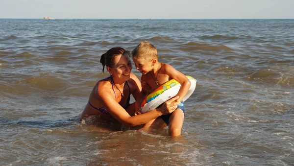 Η μητέρα και ο ήλιος κολυμπούν στη θάλασσα. Καλοκαιρινές διακοπές στη θάλασσα παραλία. — Φωτογραφία Αρχείου