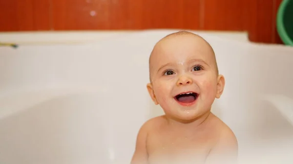 Bambino divertente che gioca con l'acqua in un bagno. Bagni per bambini . — Foto Stock