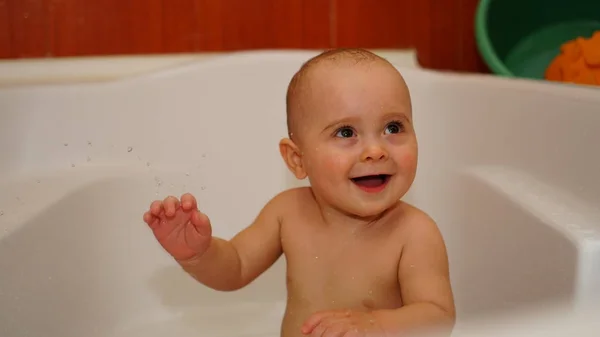 Bambino divertente che gioca con l'acqua in un bagno. Bagni per bambini . — Foto Stock