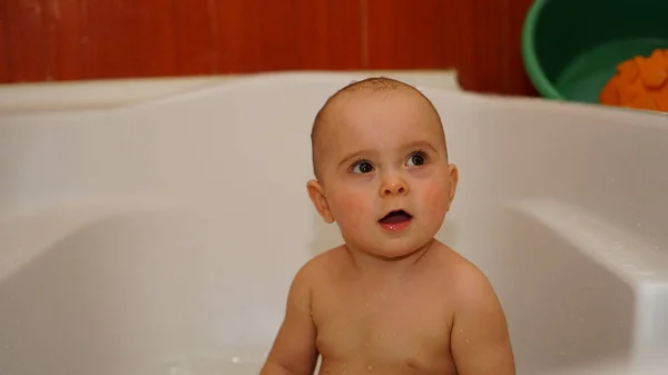 Bambino divertente che gioca con l'acqua in un bagno. Bagni per bambini . — Foto Stock