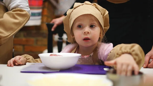 Little girl in a cooking caps playing in cafe. Concept of cooking classes