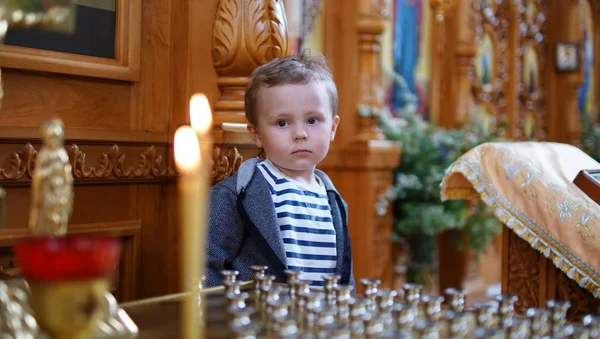 Kleine jongen kijken naar de kaars in orthodoxe kerk, eerste bezoek aan akerk — Stockfoto