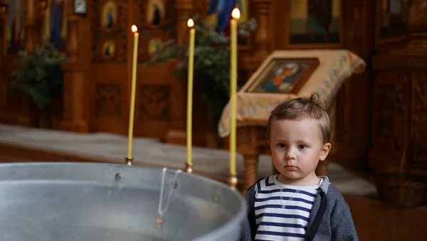 Kleine jongen in de buurt van het lettertype in orthodoxe kerk, eerste bezoek aan akerk — Stockfoto