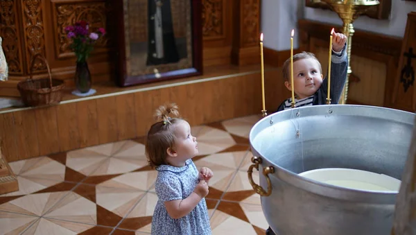 Kleine jongen en meisje in de buurt van het lettertype in orthodoxe kerk, eerste bezoek aan een kerk — Stockfoto