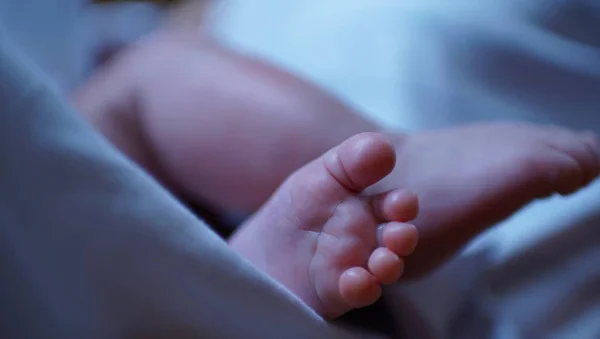 Το πόδι του μωρού στο κρεβάτι με την μπλε πάνα. — Φωτογραφία Αρχείου