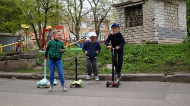 Oyun alanında kick scooter sürme üç sevimli küçük çocuklar