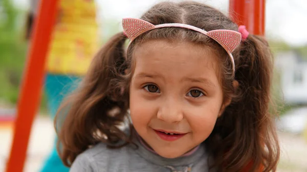 Ritratto di bambina sorridente felice che gioca al parco giochi in estate — Foto Stock