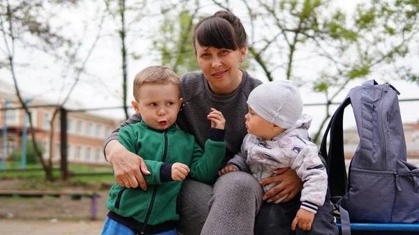 Щаслива мати і двоє маленьких дітей позують разом на дитячому майданчику влітку — стокове фото