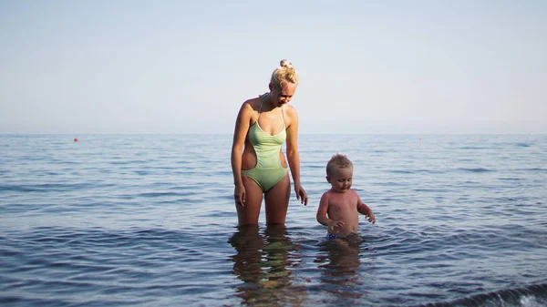 Mutter und ihr kleiner Sohn spielen und haben Spaß im Wasser. — Stockfoto