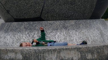 Yakışıklı sevimli bir çocuk kaide üzerinde yalan