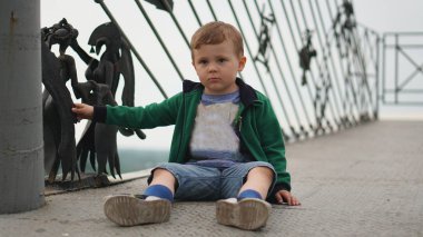 Küçük bir çocuk oyun alanı üzerinde açık havada yaz aylarında eğleniyor. Bir slayt üzerinde yürümeye başlayan çocuk.