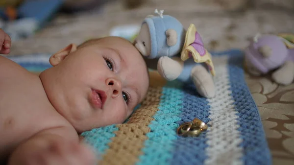 Симпатичный счастливый 3-месячный мальчик лежит с игрушкой и кольцом — стоковое фото