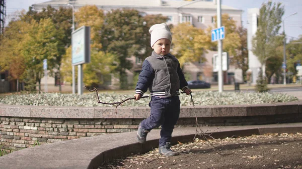 Mignon petit garçon debout sur le lit de fleurs urbain en automne . — Photo