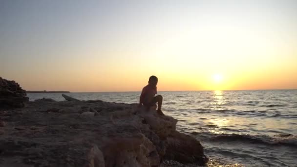 Silhouet Van Een Kleine Jongen Springen Kust Rotsen Tegen Een — Stockvideo