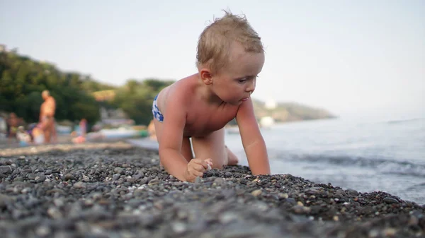 Niedliches Kind krabbelt im Schatten am Strand. — Stockfoto