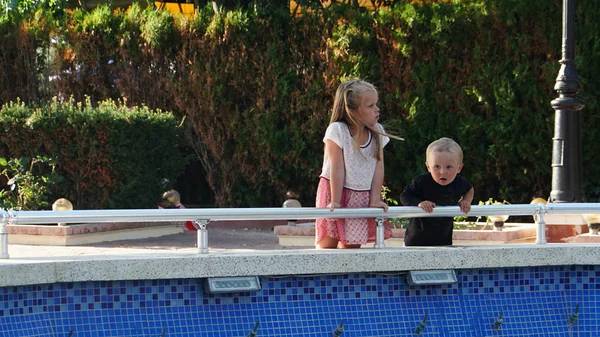 休暇中にプールの近くに小さな男の子と女の子の肖像画. — ストック写真