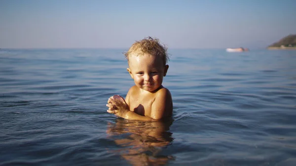 Mały chłopiec idzie do wody, aby pływać i patrzy na dno morza. — Zdjęcie stockowe