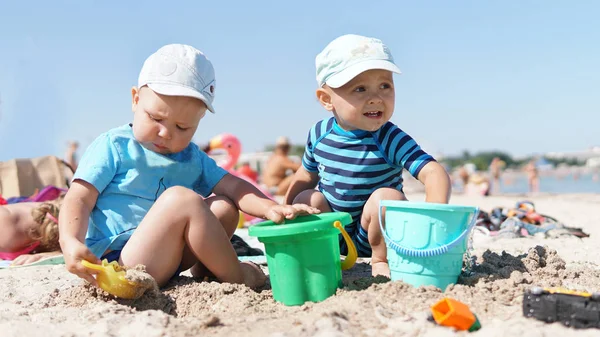 Dwa małe dzieci na plaży bawią się piaskiem — Zdjęcie stockowe