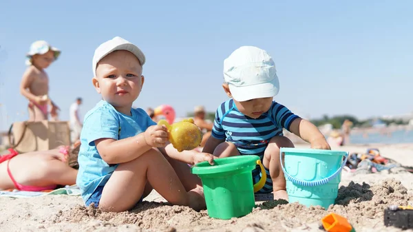 Dwa małe dzieci na plaży bawią się piaskiem — Zdjęcie stockowe
