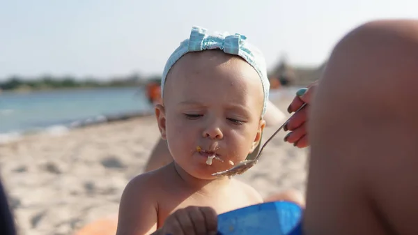 Dziecko na plaży morskiej jedzenia owsiankę. Wybrzeże Morza na tle — Zdjęcie stockowe