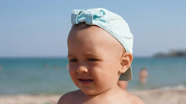 Deniz sahilinde duran mavi şapkalı üzgün çocuğun yakın çekim portresi — Stok fotoğraf