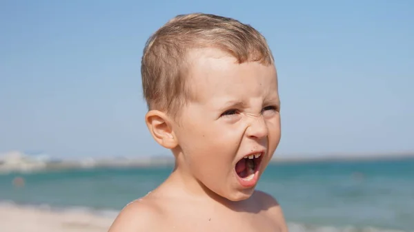 Primer plano retrato de niño gritando con pelo rubio en la playa de mar — Foto de Stock