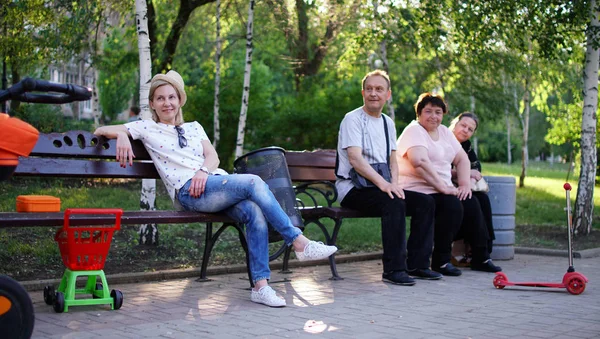 Група людей похилого віку та молода доросла жінка, яка сидить на лавці в парку. — стокове фото