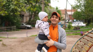 Yakışıklı gülümseyen yetişkin baba kollarında sevimli küçük bebek tutarak