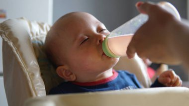 Bebek arabasında bir şişeden suyu içen sevimli bebek