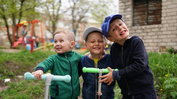 Trois adorables petits enfants chevauchant sur des scooters de coup de pied à l'aire de jeux — Photo