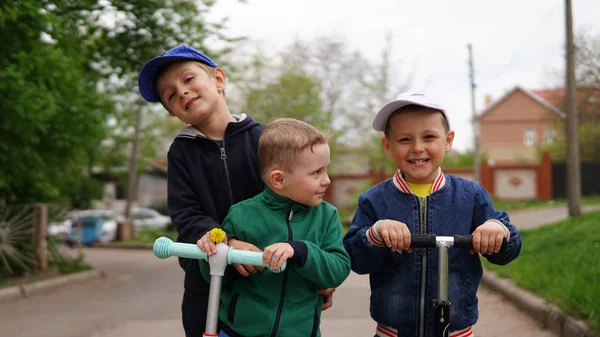 Trois adorables petits enfants chevauchant sur des scooters de coup de pied à l'aire de jeux — Photo