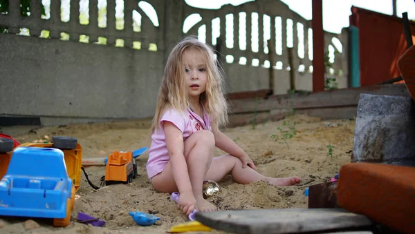Дитина грає на піску у дворі щаслива кавказька дівчинка. Малюк з піщаними іграшками — стокове фото