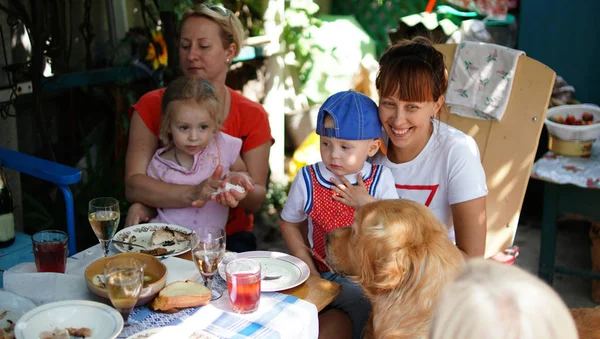 Two mom with children sitting at table with dog in countryside