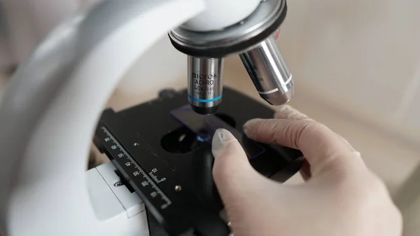 Laboratory technician makes fine-tuning of the microscope to study the samples — Stock Photo, Image