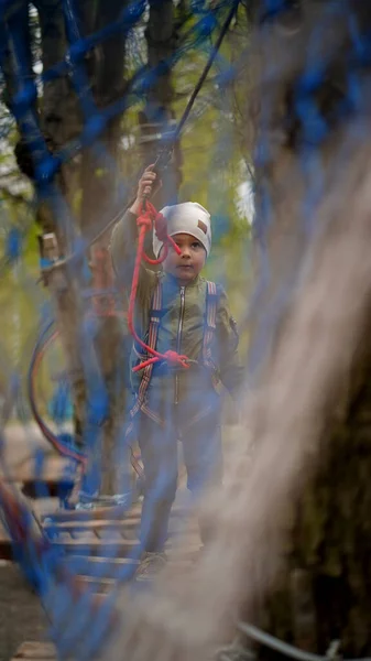 Brave little boy walking on a rope bridge in an adventure rope park.