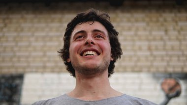 Basketbol oynadıktan sonra sahada poz veren gülümseyen genç bir adam.