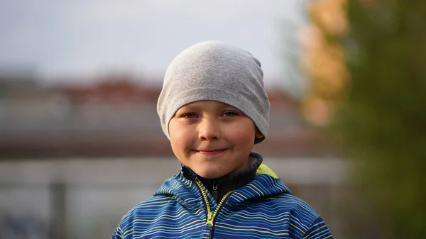 Portret Uśmiechniętego Chłopca Niebieskiej Kurtce Szarej Czapce Szkolnym Placu Zabaw — Zdjęcie stockowe