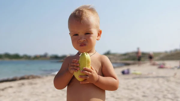 Słodkie Dziecko Stojące Plaży Jedzące Smaczną Gruszkę Patrzące Aparat Bardzo — Zdjęcie stockowe