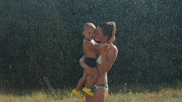 Junge Mutter Steht Wasserspray Und Hält Lächelnden Kleinen Sohn Arm — Stockfoto