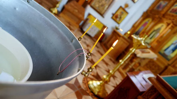 Baptismal font in a ortodoxal church . Accessories for the christening of children with cross and candles.