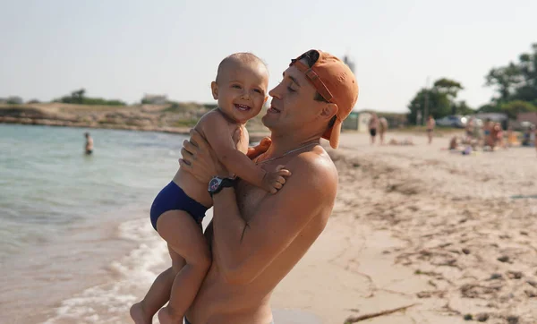小さな子供とビーチで彼の慎重な父親 パパは子供を抱いてる — ストック写真