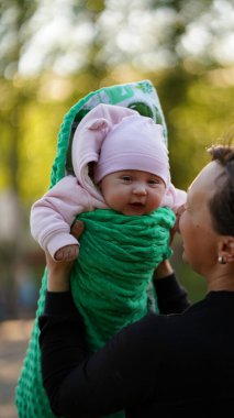 Babamın kucağında yeni doğmuş bir kız çocuğu var. Yeşil kemerli bebek neşeyle gülüyor