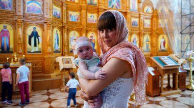 Ortodoks Kilisesi 'nde türbanlı kadınların kollarında küçük bir kız çocuğu, ilk ziyareti ve kilisede ilk izlenimi.