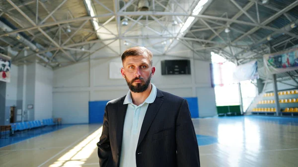 A young man with beard in a blazer in game basketball court. Man standing alone in middle of court